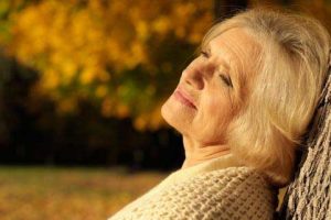 An elderly woman looking sad and off in thought